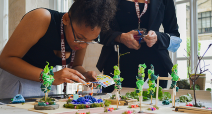 Students with InvestIN lanyards assembling small architectural models with plants and structures, InvestIN Architect Summer Experience in London