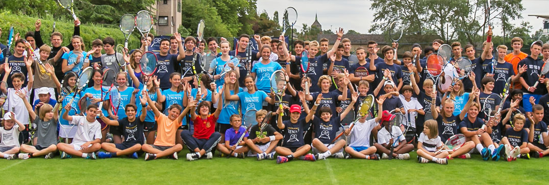 Large group photo of players and coaches in camp shirts on the lawn at the Oxford tennis camp