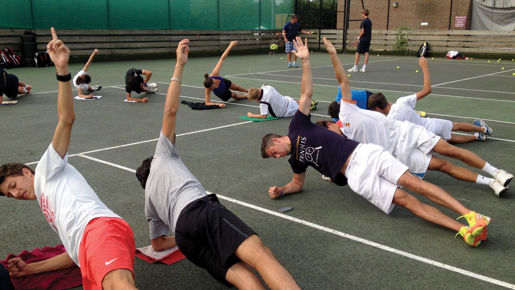 Players stretching on court during a fitness session at the Oxford tennis camp