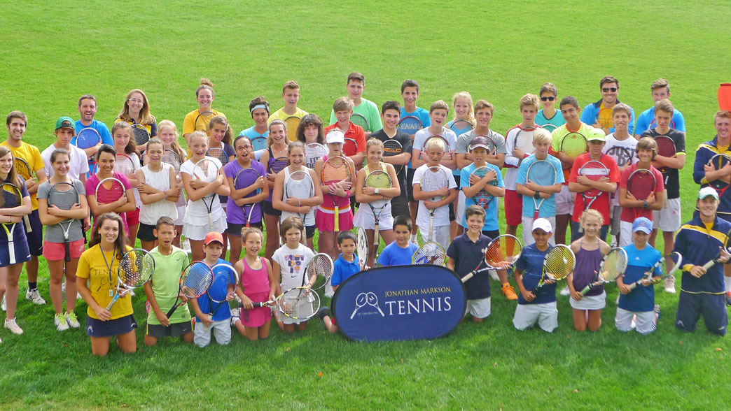 Players and coaches gathered for a group photo with rackets on the lawn at the Oxford tennis camp