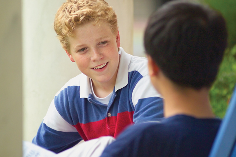 Two students facing each other in close conversation during a debate session