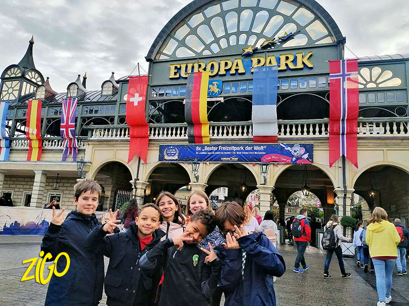 Group of children in front of the Europa Park main entrance, hung with the flags of the European themed quarters