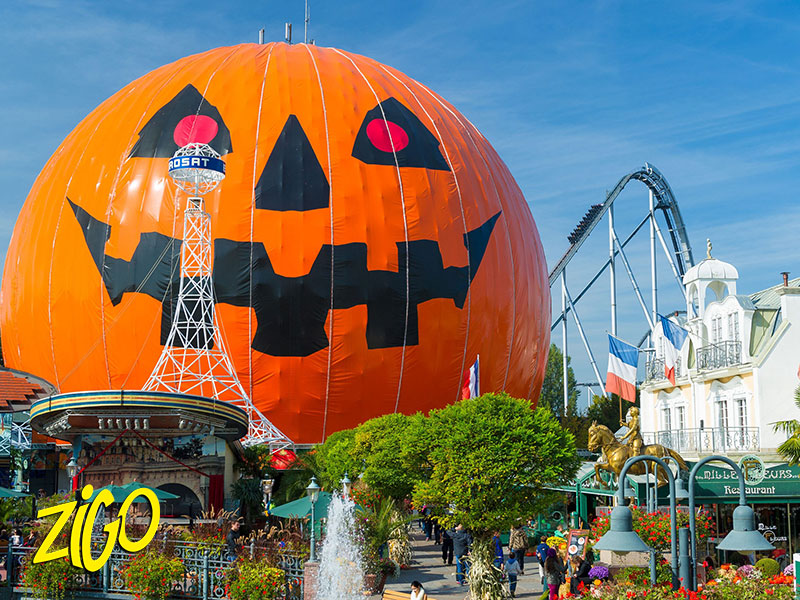 Giant carved pumpkin set up for the autumn season at Europa Park, with a roller coaster in the background