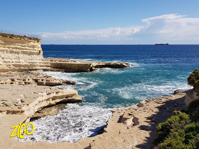 Flat limestone shelves and clear natural pools along a rocky stretch of the Maltese coast