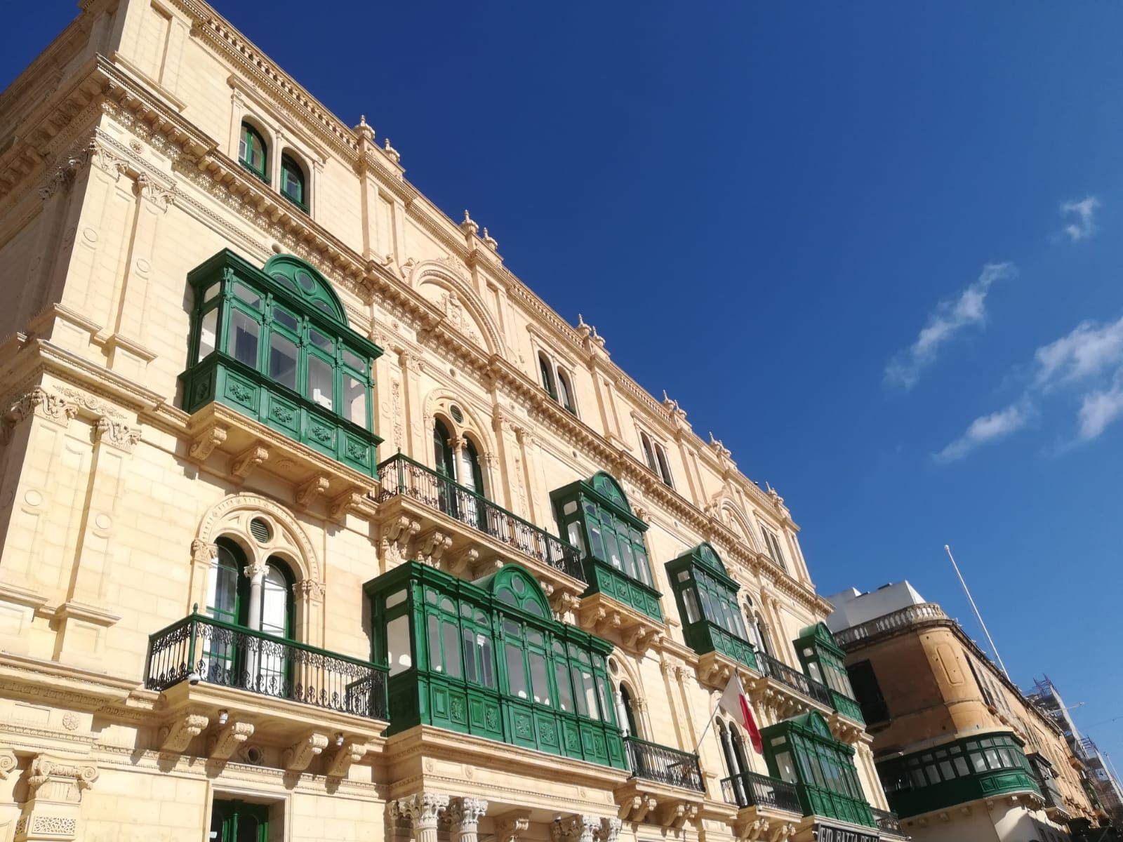 Facade of a Maltese townhouse with rows of green enclosed wooden balconies