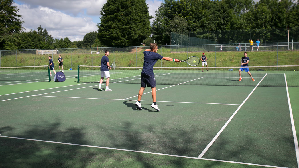 Players in a doubles rally on the hard courts at the Brighton tennis camp