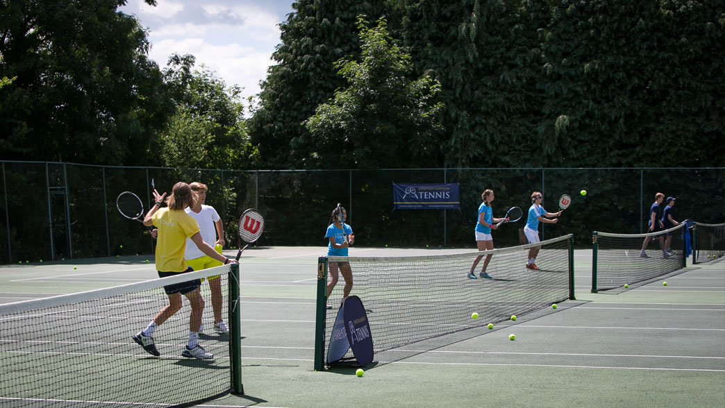Coaching session with players spread across the hard courts at the Brighton tennis camp