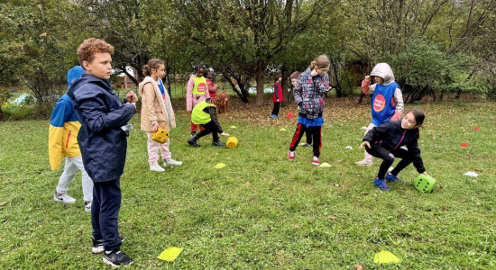 Children in warm coats playing a ball-and-cone team game on the grass at the Manoir du Viginet centre, Saint-Nectaire
