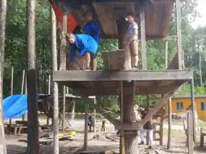 Children building walls and roof of the platform tree house in the forest at Kindererholungszentrum Am Braunsteich