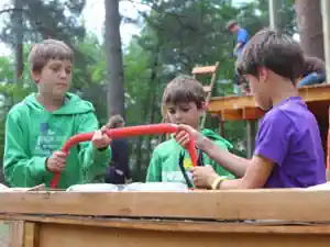 Two boys sawing a beam for the tree house with a bow saw at the Braunsteich camp