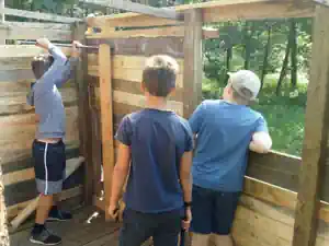 Three boys fixing the wooden side walls of the tree house