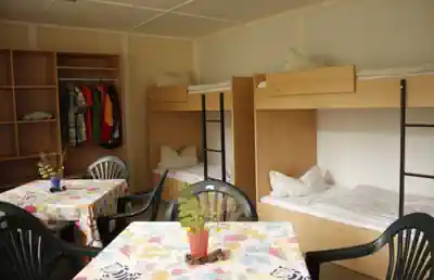 Four-bed room with bunk beds, tables and wardrobe at Kindererholungszentrum Am Braunsteich