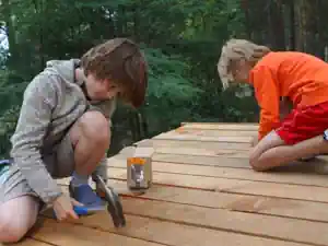 Two boys hammering the floorboards of the tree house platform