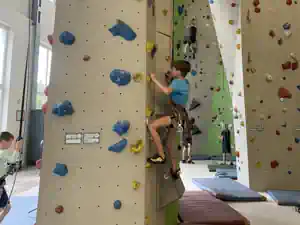 Boy climbing a wall in an indoor climbing hall during the Bielatal climbing camp