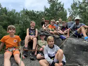 Group of children sitting roped up on a rock summit in the Elbe Sandstone Mountains