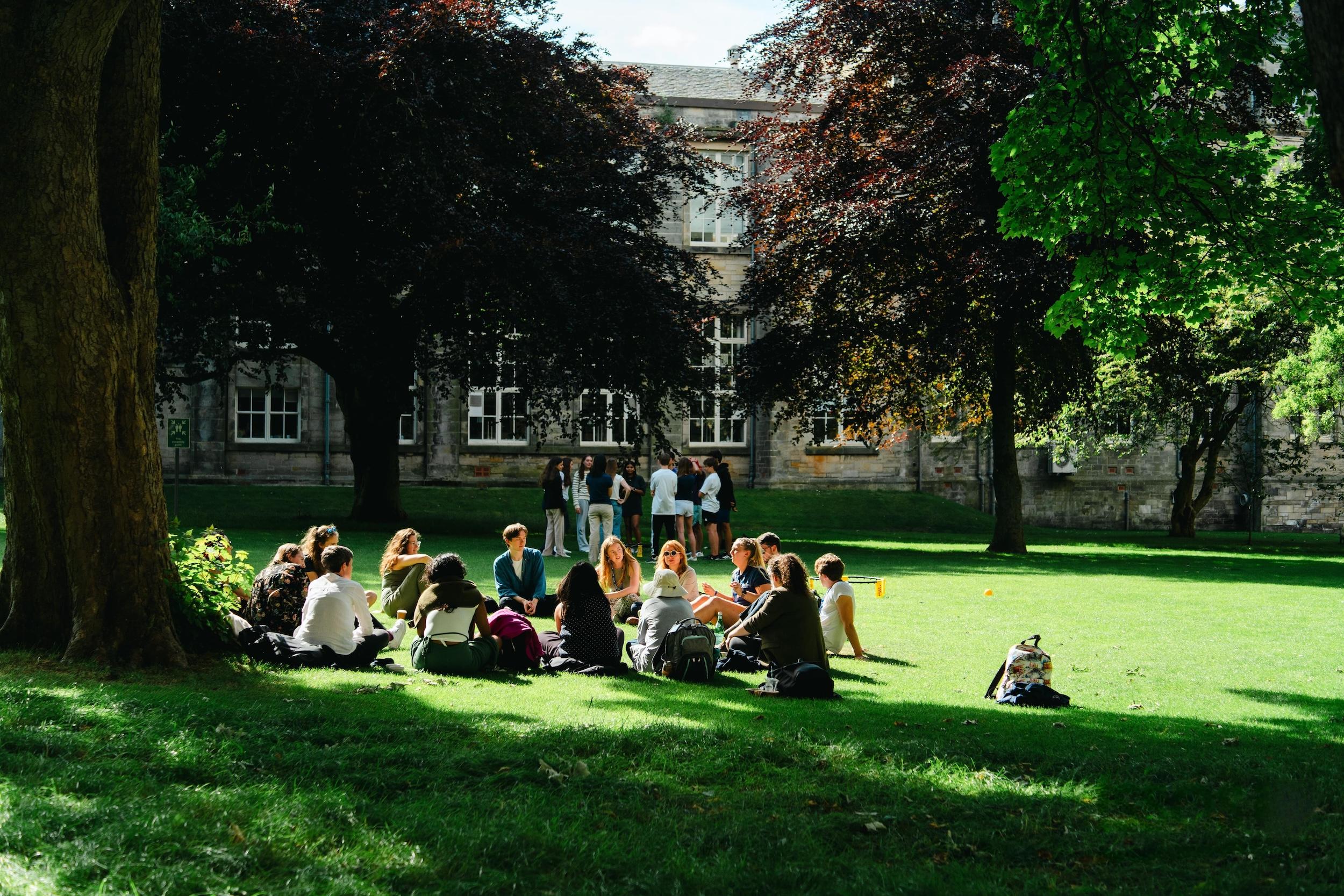 Students sitting in groups on the lawn at St Andrews, enjoying time outside during ISSOS summer school.