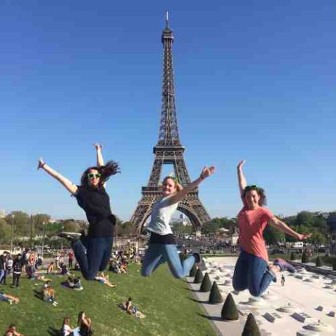 Participants with arms raised in front of the Eiffel Tower on the sightseeing tour