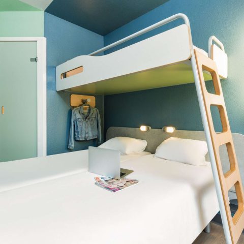 Hotel room with a bunk bed, reading lights and an open shelf