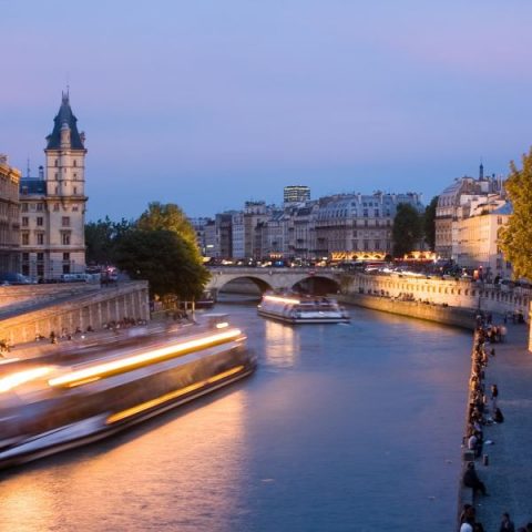 Evening illumination cruise: a lit boat on the Seine between floodlit riverbanks