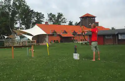 Boy practising archery on the lawn in front of Sporthostel Schubybeach