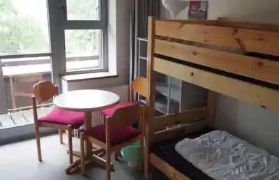 Room with wooden bunk bed, table and chairs at Sporthostel Schubybeach