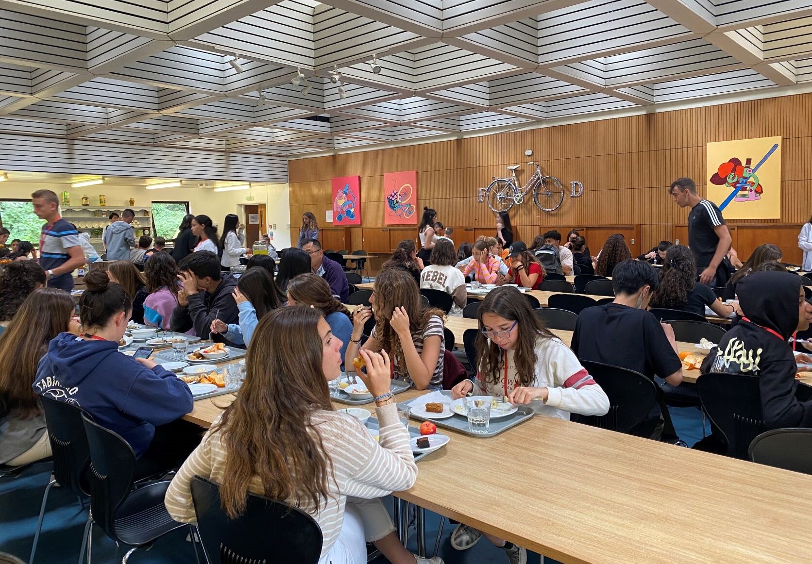 Summer school students having a meal at long tables in the wood-panelled dining hall of Ashford School, Ashford, Kent