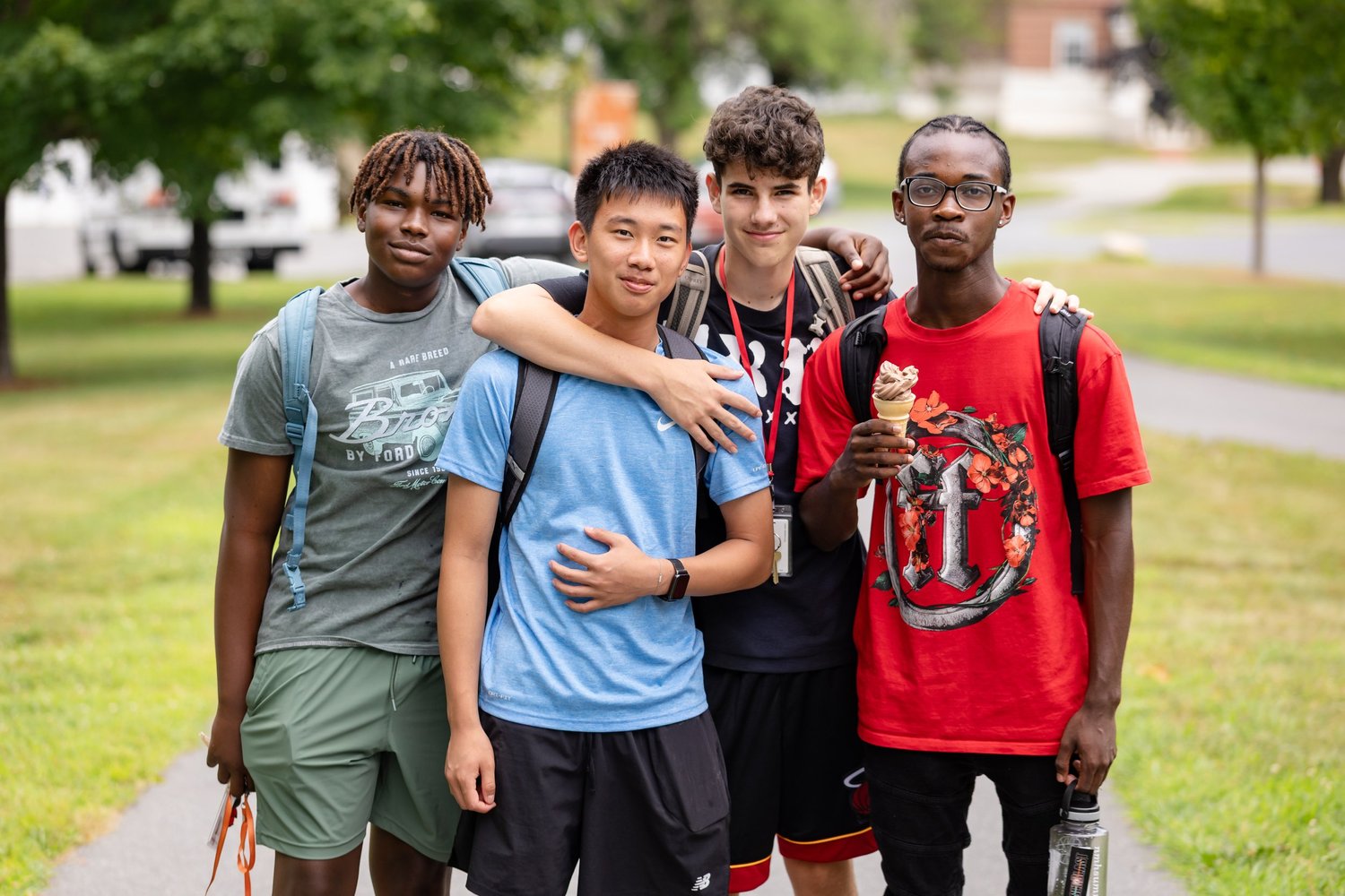 Four students standing together on the campus lawn with ice creams
