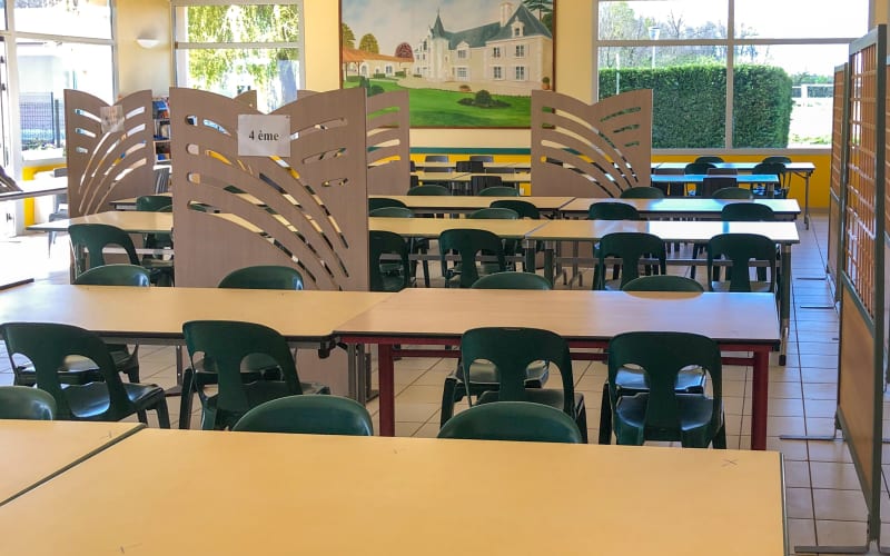 A room at the centre with wooden tables and chairs and a painted mural, looking out through glazing onto the grounds