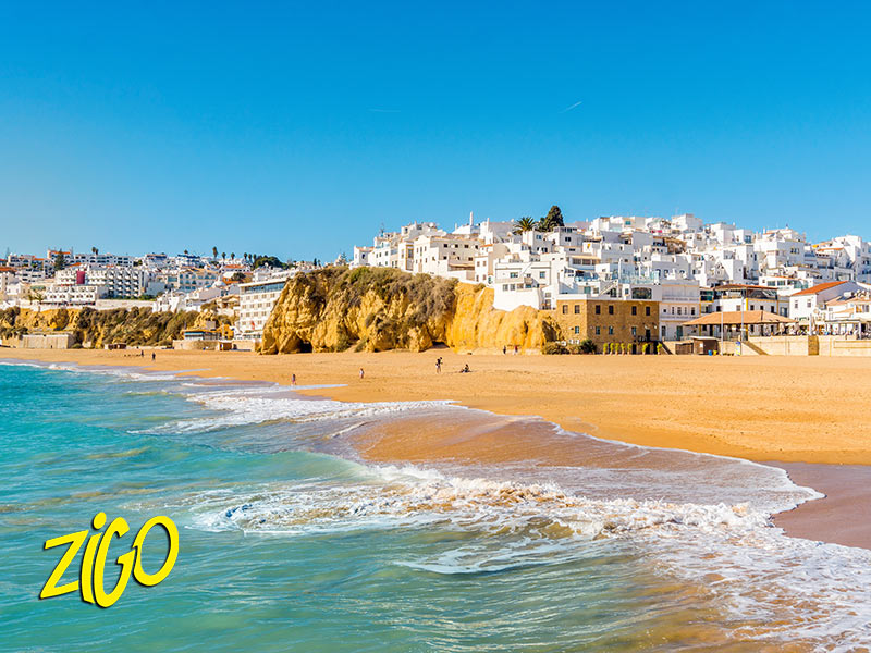 Sandy beach below the white houses of Albufeira, cliffs closing the bay on one side