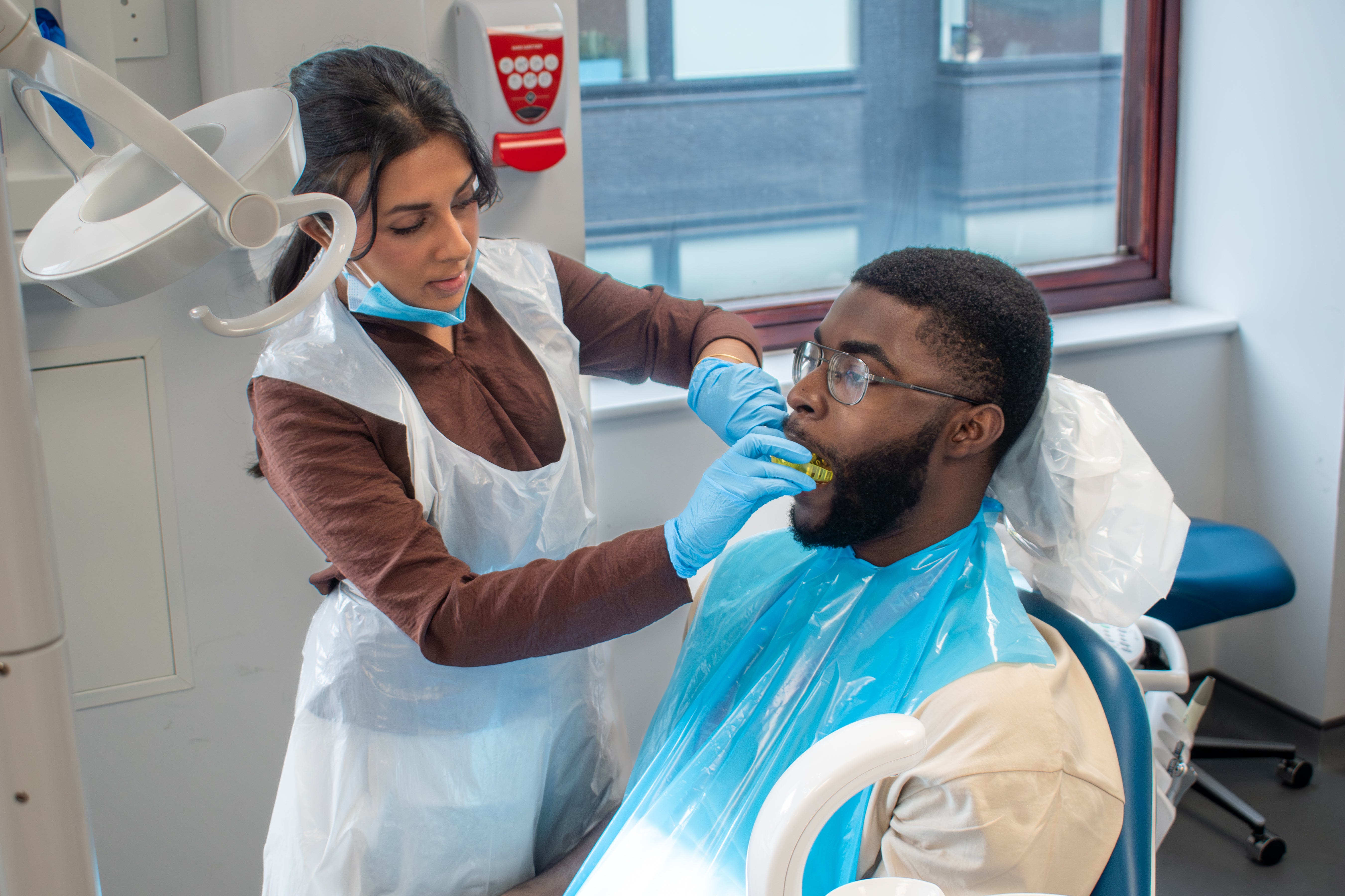 Dental professional demonstrating an examination on a seated volunteer in a dental chair, InvestIN Dentist Summer Experience in London