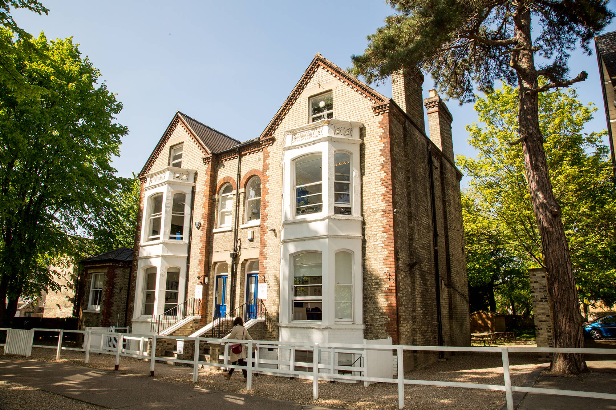 Victorian school building with bay windows and trees in front, the Station Road site in Cambridge where the course is taught