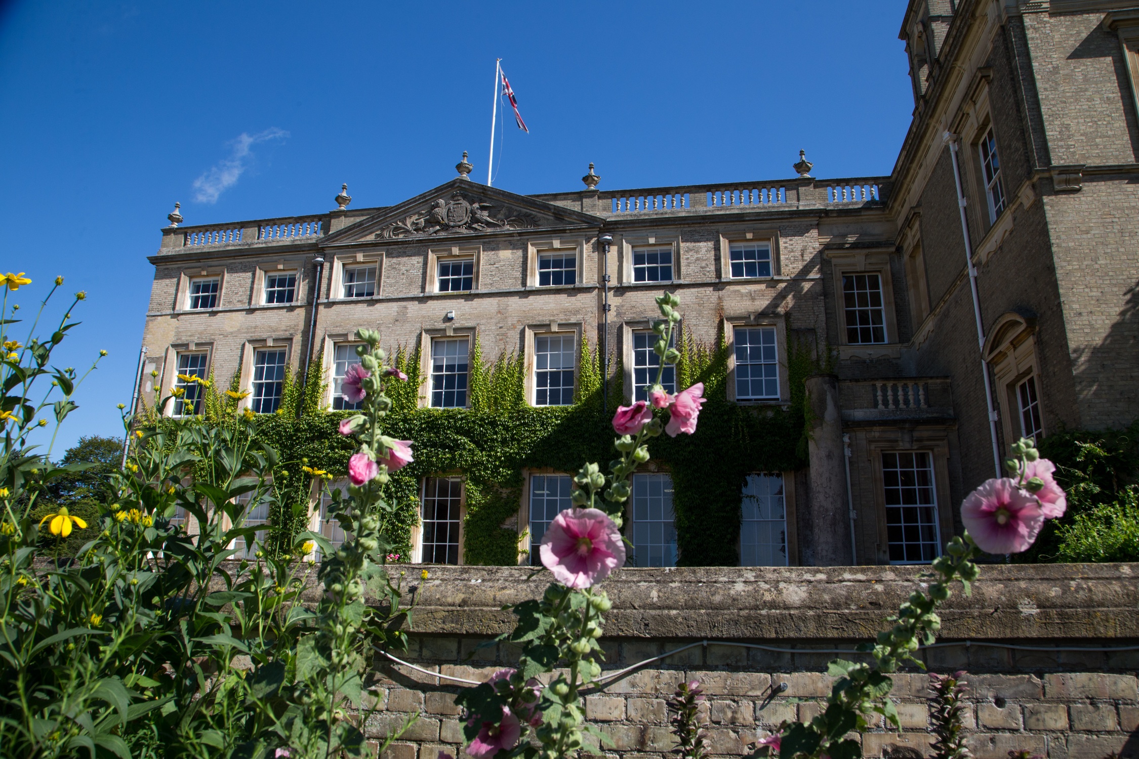 Georgian country house of the Culford School estate seen behind flowering shrubs