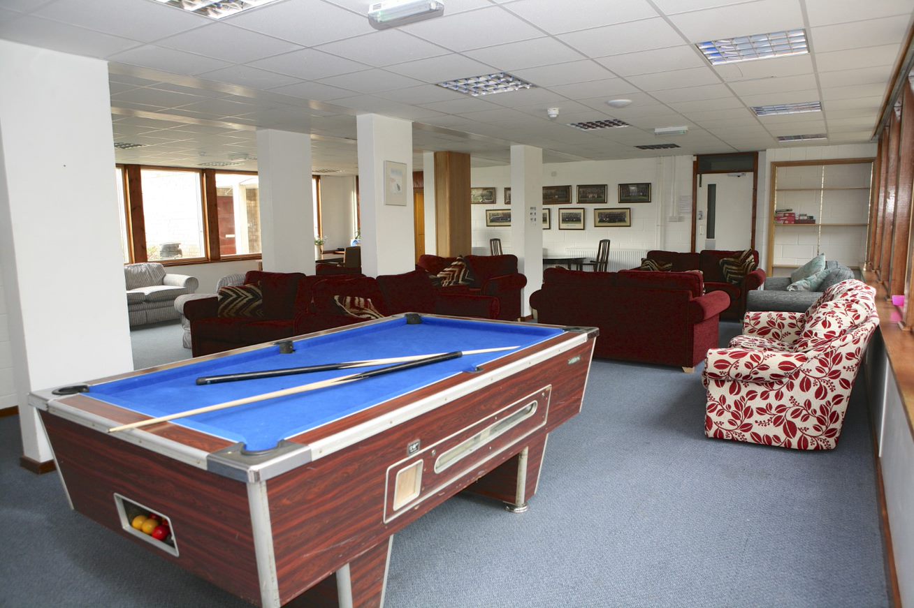 Common room in a boarding house with a pool table, sofas and armchairs