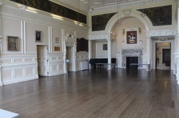 Large panelled hall with a wooden floor and tall windows inside the school