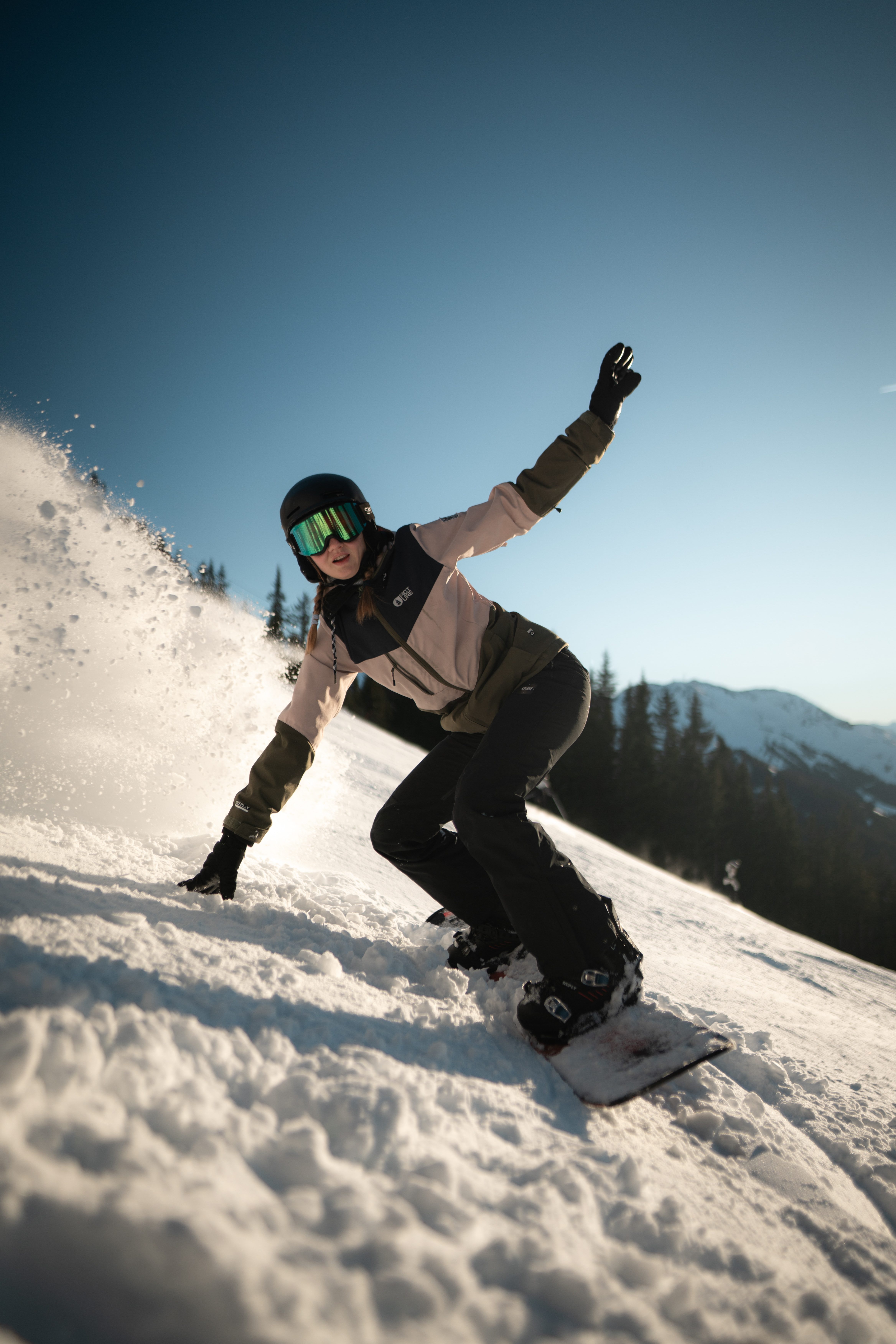 A camp guest snowboarding on the piste in St. Johann in Tirol