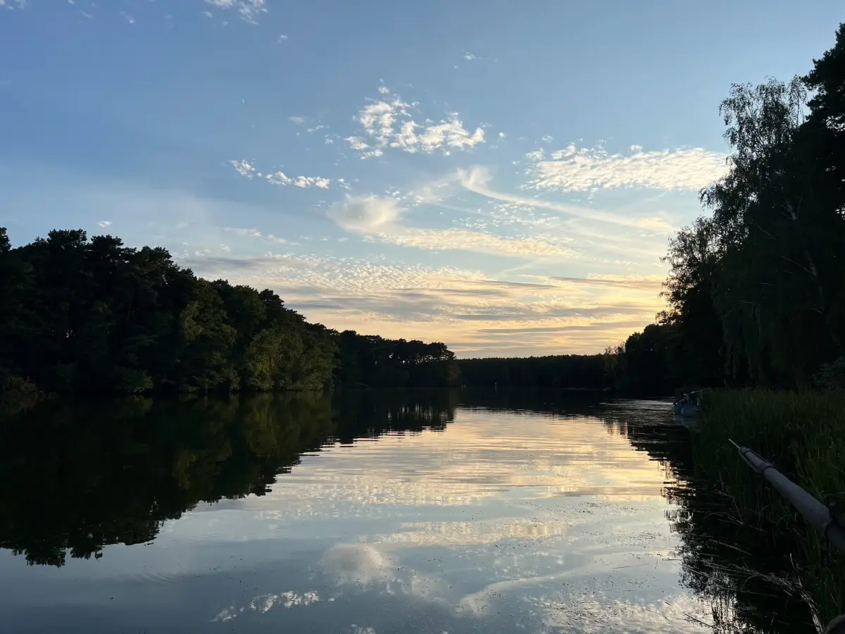The Huschte-See at dusk, still water reflecting the treeline and the evening sky
