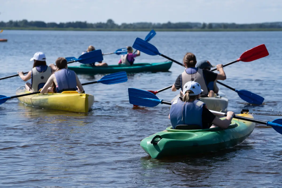Children paddling yellow and green canoes out on the Huschte-See at Prieros