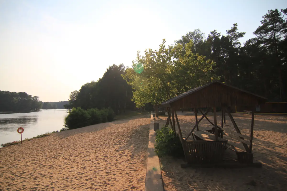 The sandy camp beach on the Huschte-See with a wooden shelter at the waterline