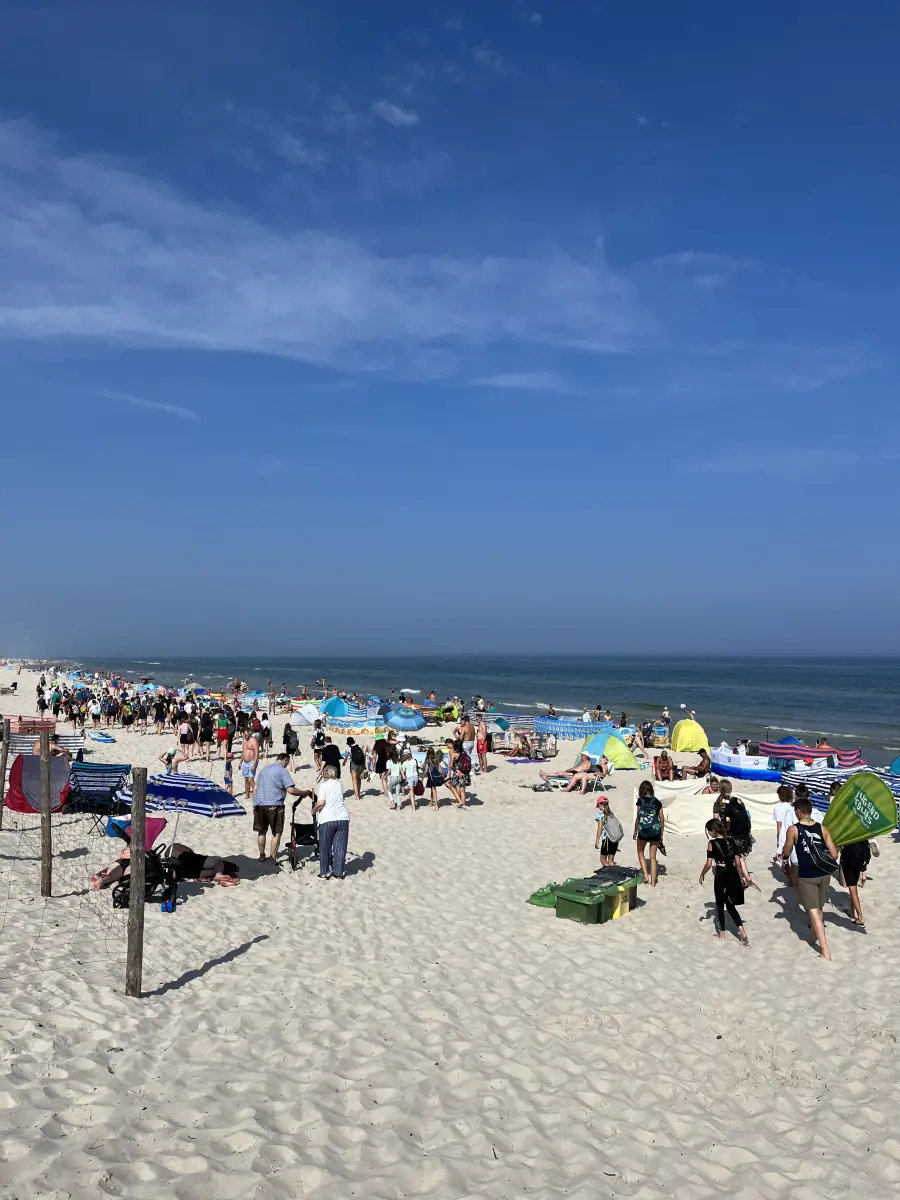 The wide Baltic beach at Dzwirzyno busy with bathers and beach shelters, the sea beyond