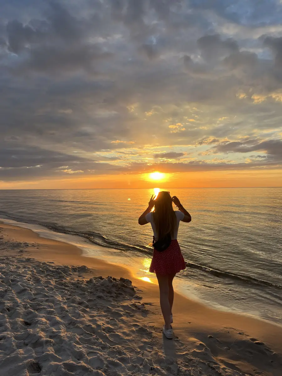 Sunset over the Baltic with a camper silhouetted at the waterline taking a photograph