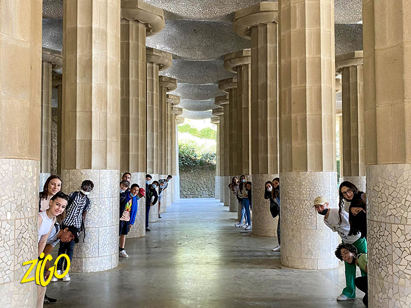 Group walking through the leaning stone colonnade of Park Güell