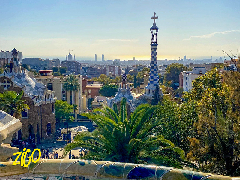 Barcelona spread out to the sea seen from the terrace of Park Güell, palms and agaves in the foreground