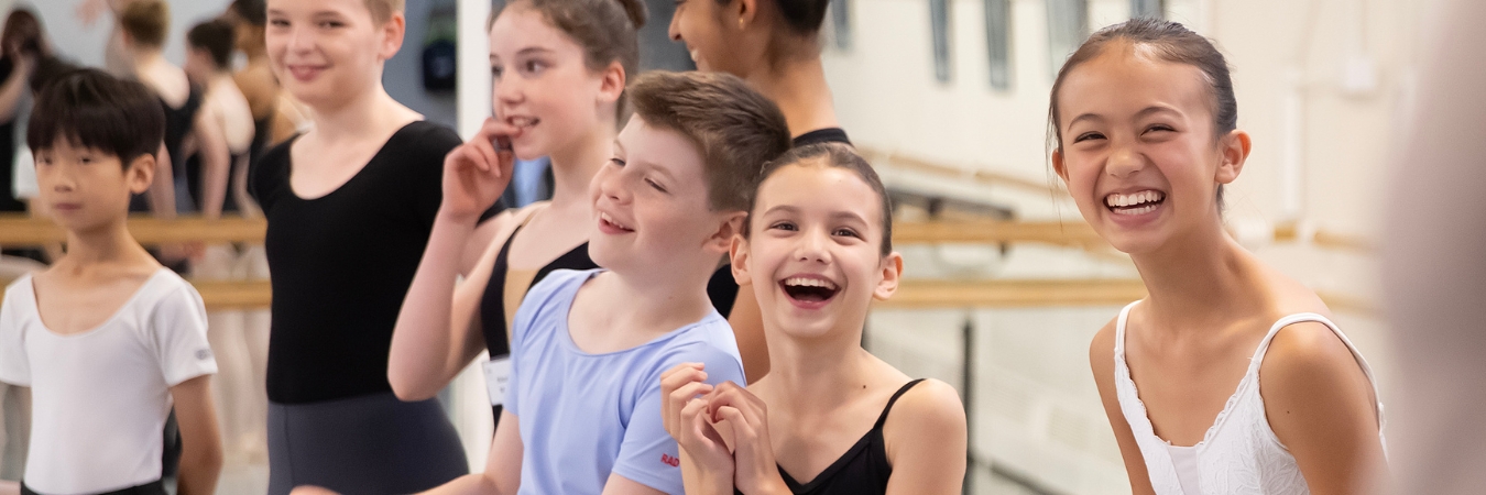 Young dancers laughing together at the barre during the Spring Intensive