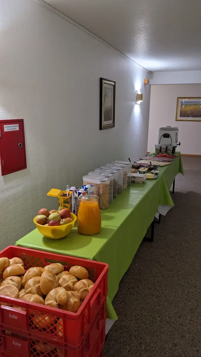 A long buffet table with cereal dispensers, fruit, juice and tableware