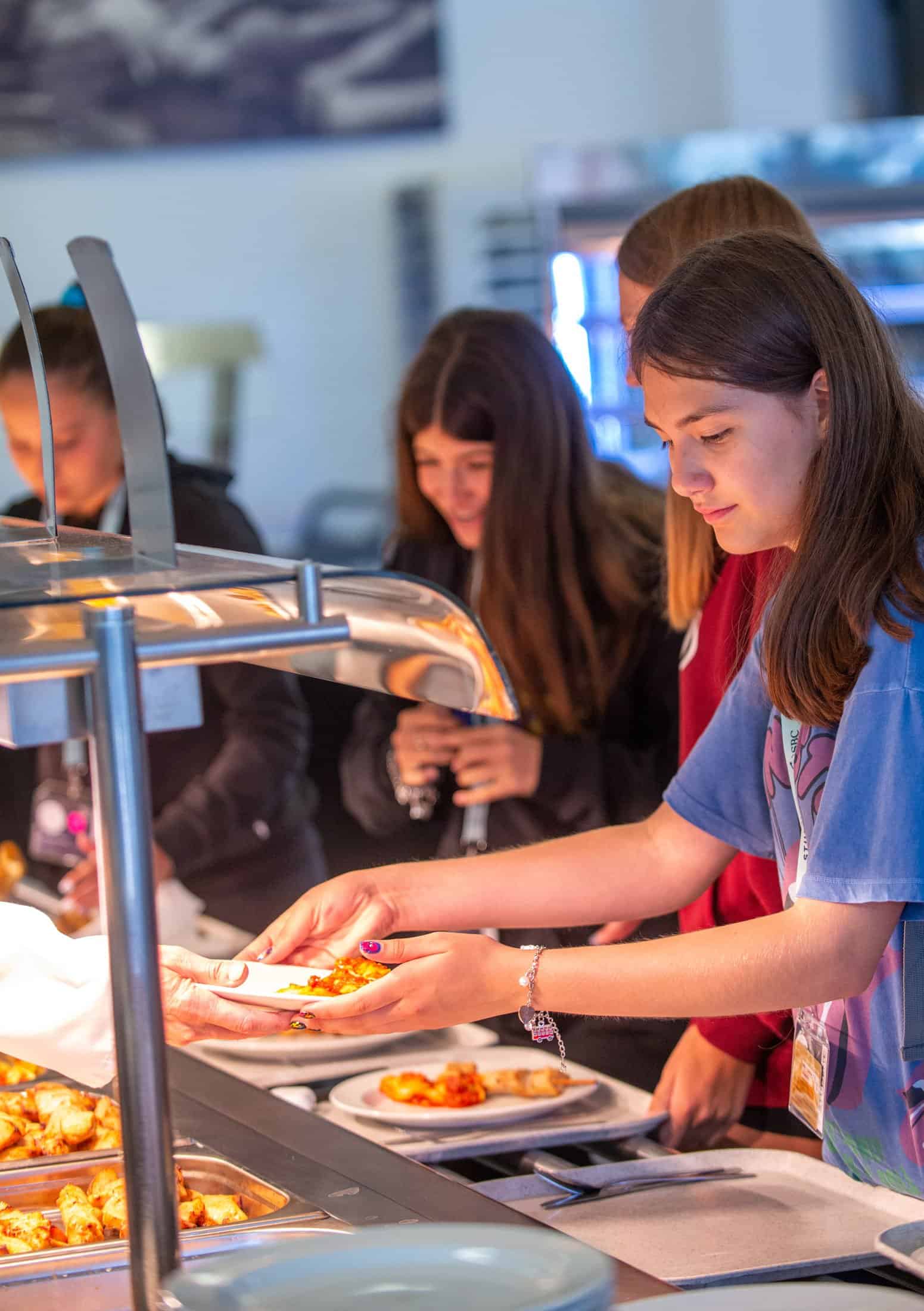 Students serve themselves hot food from the counter in the school dining hall