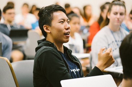 A student sitting up in her seat to answer a question during a lecture