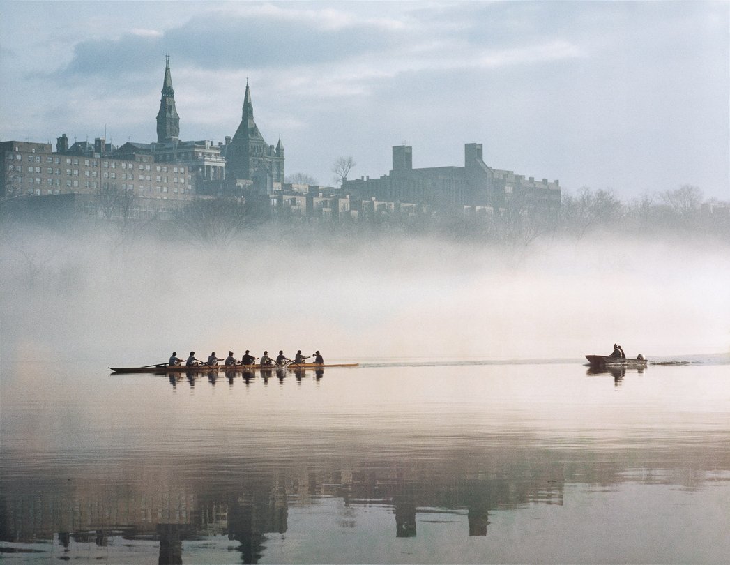 Rowing crews out on the Potomac in early morning mist, with the Georgetown campus on the bluff beyond