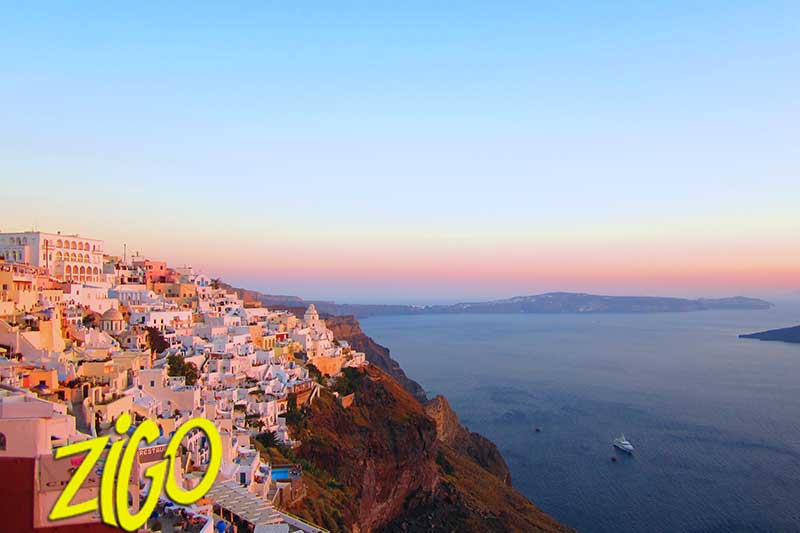 Sunset light over the caldera, the cliff-top village glowing orange above the sea