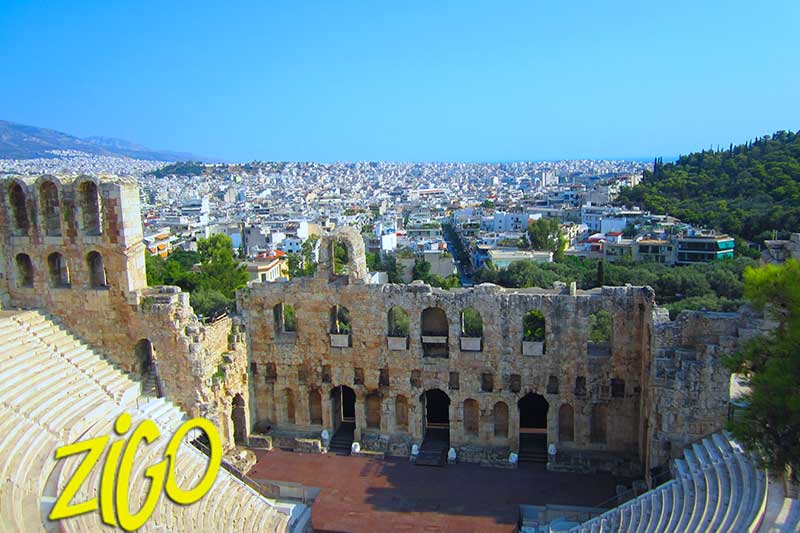 Stone tiers and arched facade of an ancient theatre on the slope of the Acropolis, Athens spreading out behind