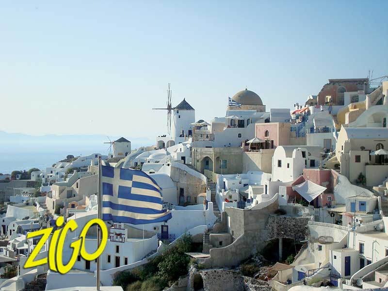 Whitewashed houses and a blue-domed chapel stacked above the caldera, a Greek flag flying